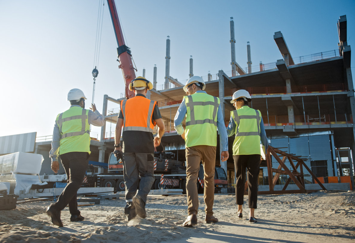 four construction workers walking away from the camera on a construction site